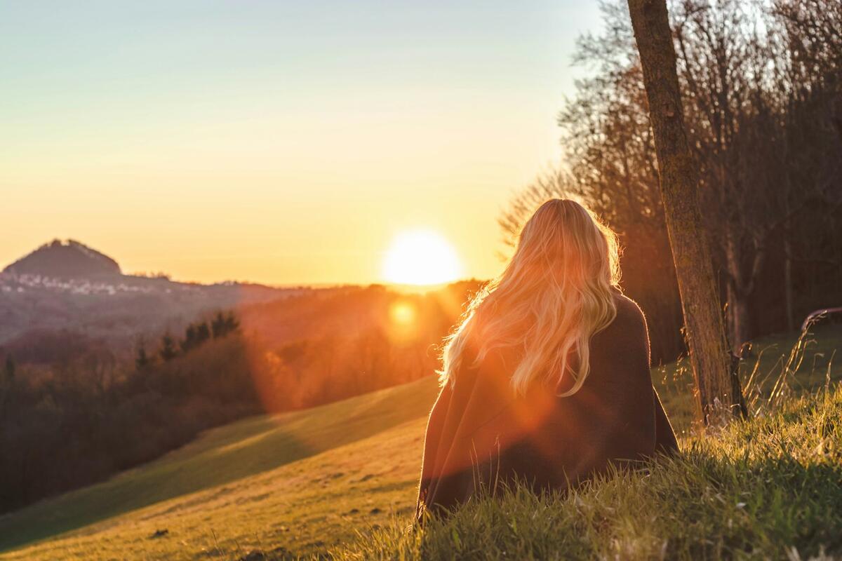 Vrouw komt tot rust in het gras in de warme avondzon